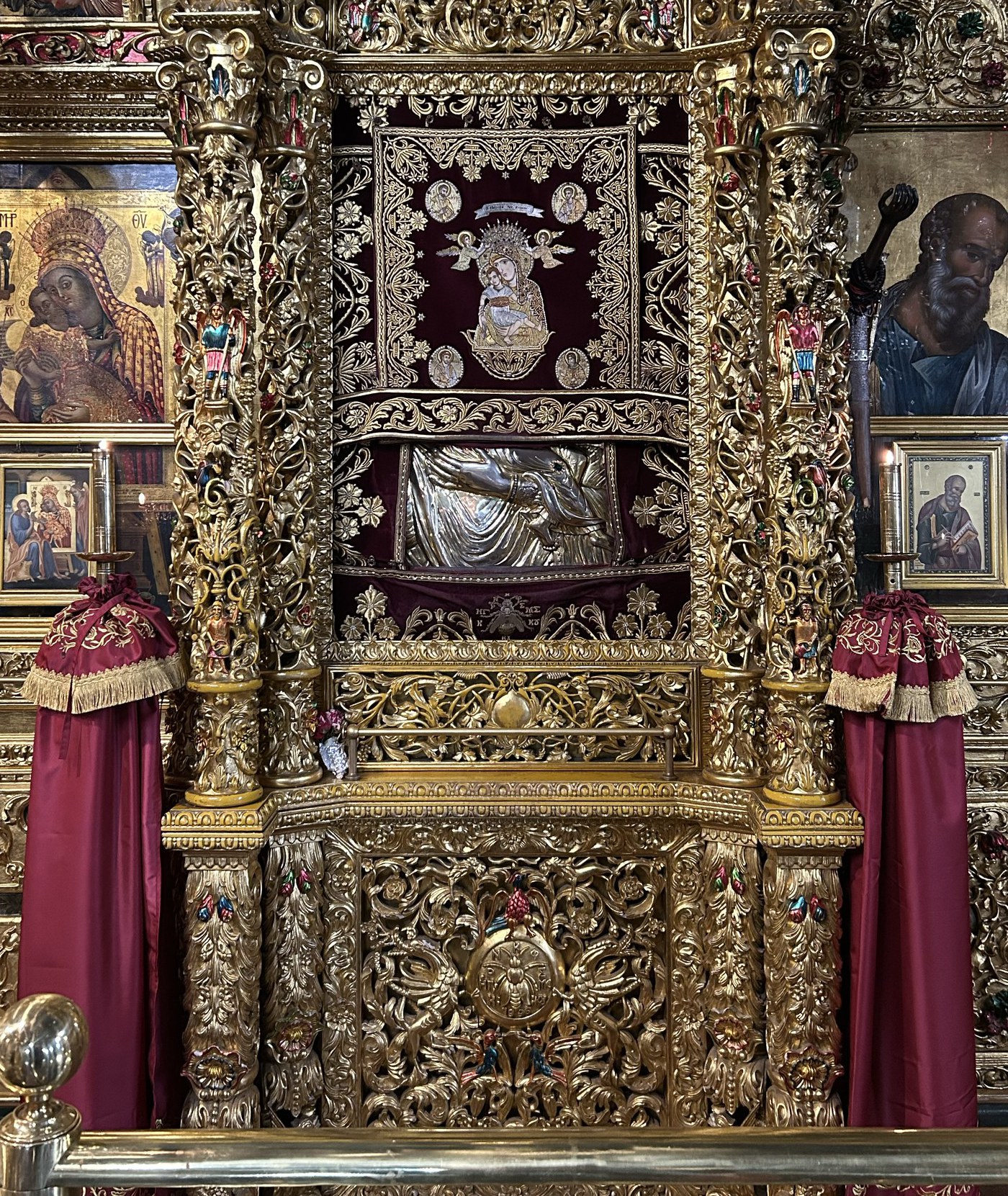 The icon of Panagia Kykkotissa upon her throne — set within the gilded baldachin of the katholikon iconostasis, the upper panel veiled in crimson and the lower panel cased in silver-gilt.